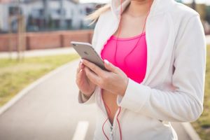 Woman with iPhone and headphones in picking a song before exercising